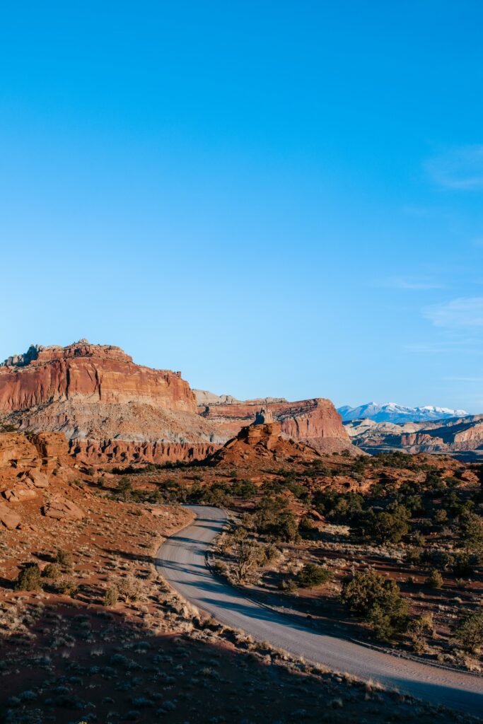 20 Best Hikes in Capitol Reef National Park 37 A paved road winds through scenic orange geologic formations on a clear day with blue sky
