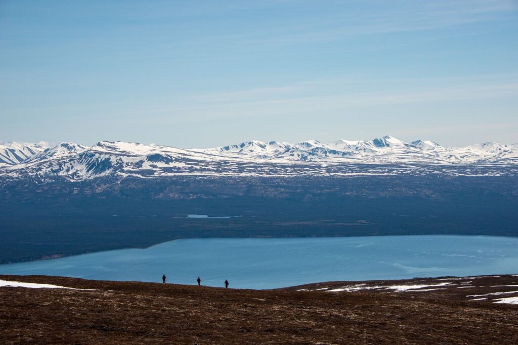 The 13 Best Things to Do in Katmai National Park: Bears and Volcanoes Galore 12 Three hikers walk along browning tundra toward a blue lake