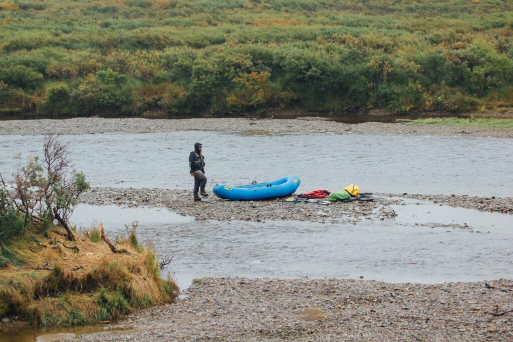The 13 Best Things to Do in Katmai National Park: Bears and Volcanoes Galore 16 A rafting guide waits next to a blue boat on the shoreline