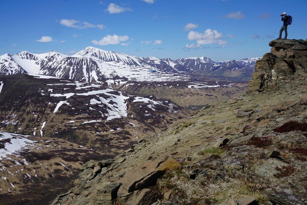 The 13 Best Things to Do in Katmai National Park: Bears and Volcanoes Galore 9 A hiker stands on an exposed rock looking down on a view over a great expanse of land known as the Valley of Ten Thousand Smokes, one of the best things to do in Katmai National Park