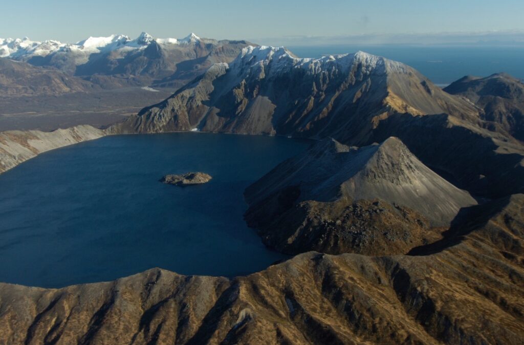 The Absolute BEST Time to Visit to Katmai National Park 18 A dark blue lake in the middle of a crater, seen from flight above