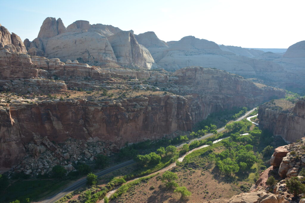 20 Best Hikes in Capitol Reef National Park 23 From an overlook, green vegetation rests below orange rock formations and monoliths