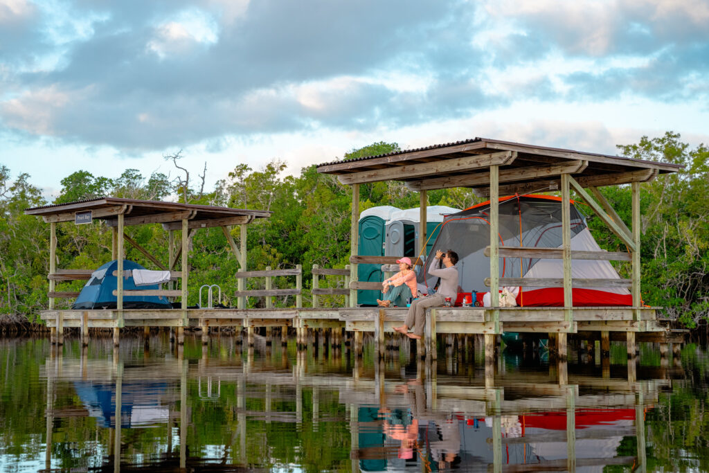 Everglades National Park Camping Guide: Everything You Need to Know 21 Two campers on an Everglades National Park camping trip sit and enjoy the view from a backcountry chickee