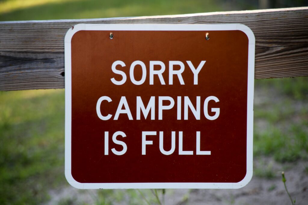 Everglades National Park Camping Guide: Everything You Need to Know 10 A brown sign with white text that reads "SORRY CAMPING IS FULL" hanging on a wooden fence.