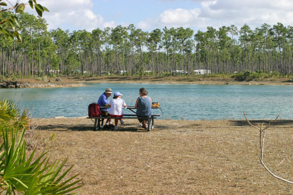 Everglades National Park Camping Guide: Everything You Need to Know 14 A group of three sit at a picnic table in front of a pond in Long Pine Key, one of the campgrounds in Everglades National Park