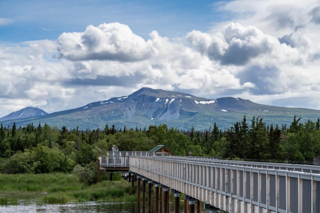 How to Get to Katmai National Park: Boats, Planes, and Bears, Oh My! 7 A wooden boardwalk leads toward mountaintops across a lake