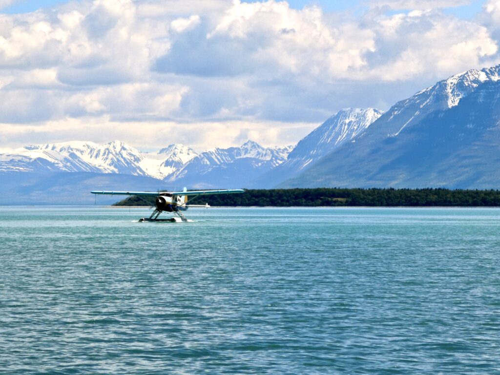 How to Get to Katmai National Park: Boats, Planes, and Bears, Oh My! 6 A float plane (how to get to Katmai National Park) preparing to land on bright blue water with snowy peaks in the background