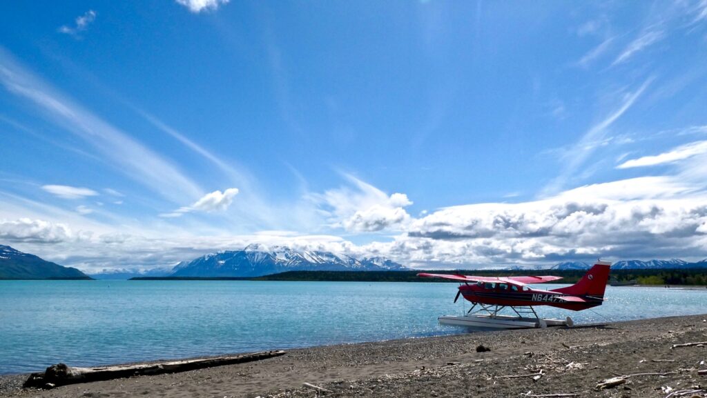How to Get to Katmai National Park: Boats, Planes, and Bears, Oh My! 22 A red floatplane sits on the shoreline of a bright blue lake