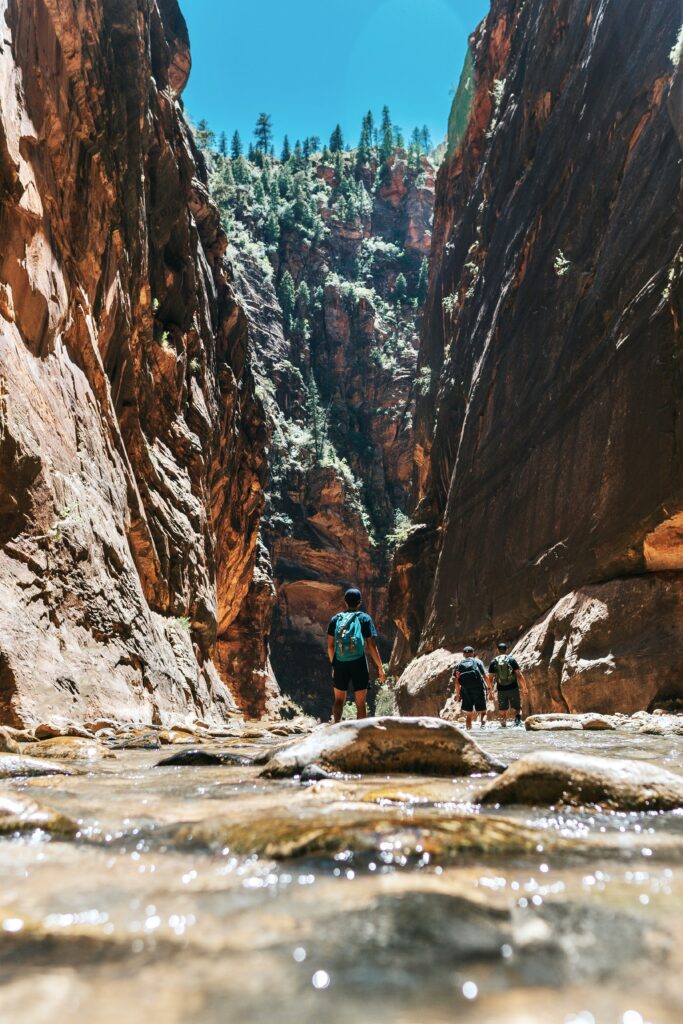 Closest Airports to Zion National Park: How to Get to Zion National Park, Utah 11 A group of hikers walk through shallow water into a canyon