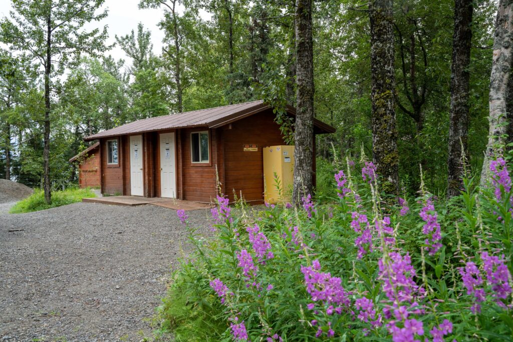 Where to Stay in Katmai National Park: Lodging, Campgrounds, and Backpacking 10 A brown building with two doors on a gravel path in the woods