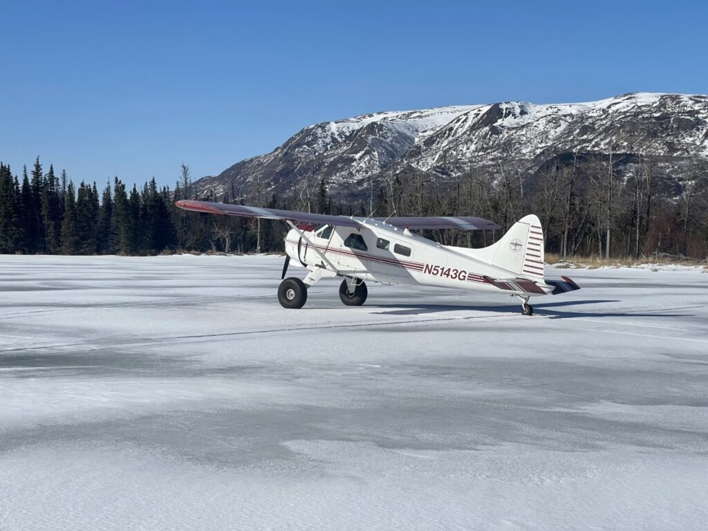 Where to Stay in Katmai National Park: Lodging, Campgrounds, and Backpacking 21 A white floatplane with red stripes sits on an icy lake