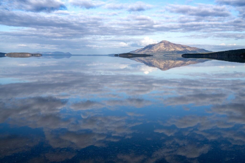 Where to Stay in Katmai National Park: Lodging, Campgrounds, and Backpacking 24 A partly cloudy sky is perfectly reflected in a still lake below