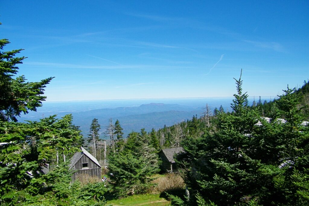 Hiking Alum Cave Trail in Great Smoky Mountains National Park 22 Under a bright blue sky, there's a wooden building with an A-frame roof and a smoky mountain view
